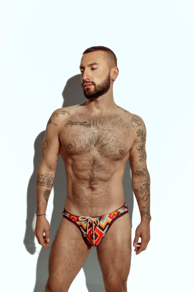 Men's swim brief featuring a bold zigzag pattern in red, orange, and yellow, ideal for gay men seeking stylish and eye-catching swimwear