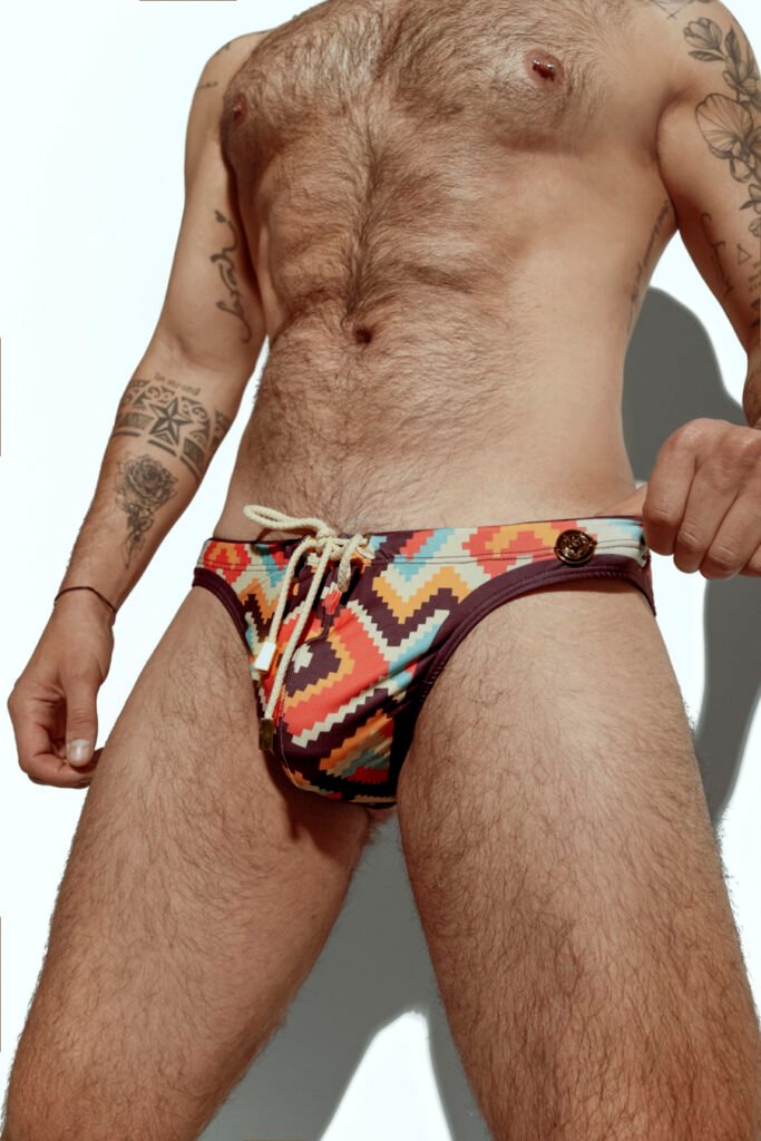 Men's swim brief featuring a bold zigzag pattern in red, orange, and yellow, ideal for gay men seeking stylish and eye-catching swimwear