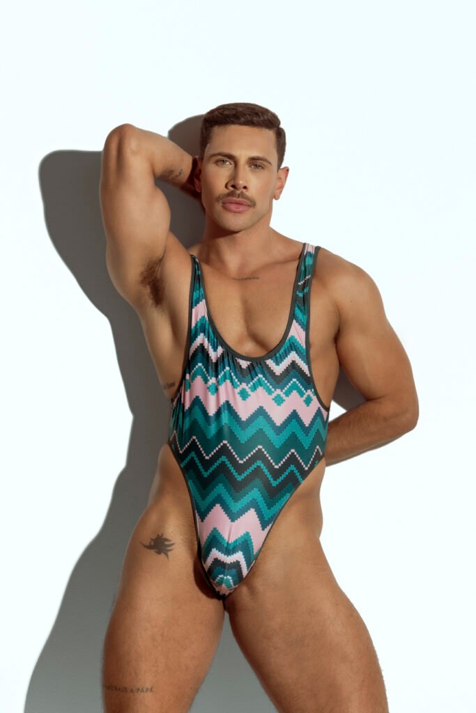 Men's high-cut swim bodysuit with bold chevron pattern in teal and pink, designed for gay men who love stylish and unique swimwear