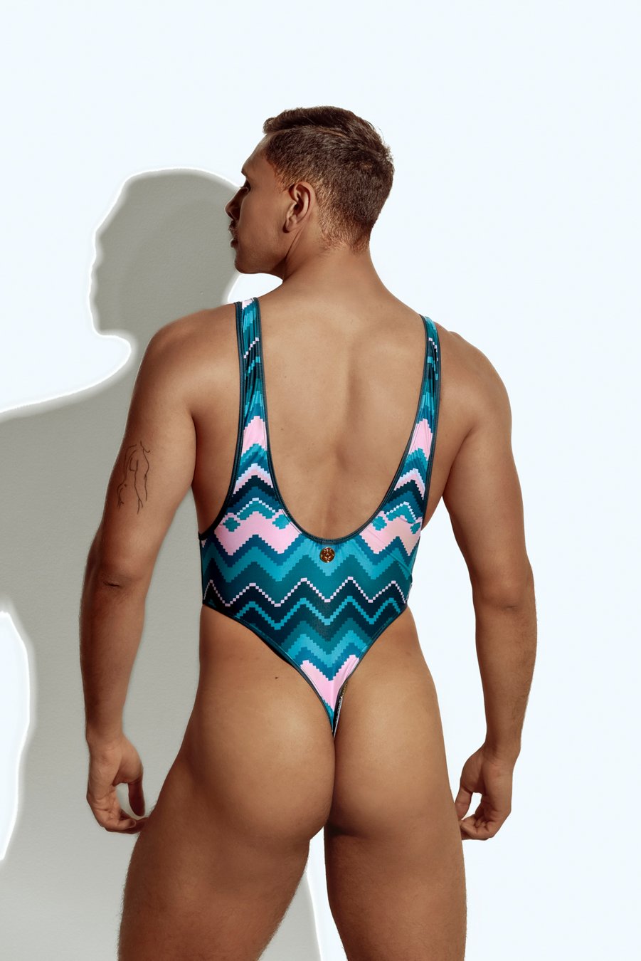 Men's high-cut swim bodysuit with bold chevron pattern in teal and pink, designed for gay men who love stylish and unique swimwear