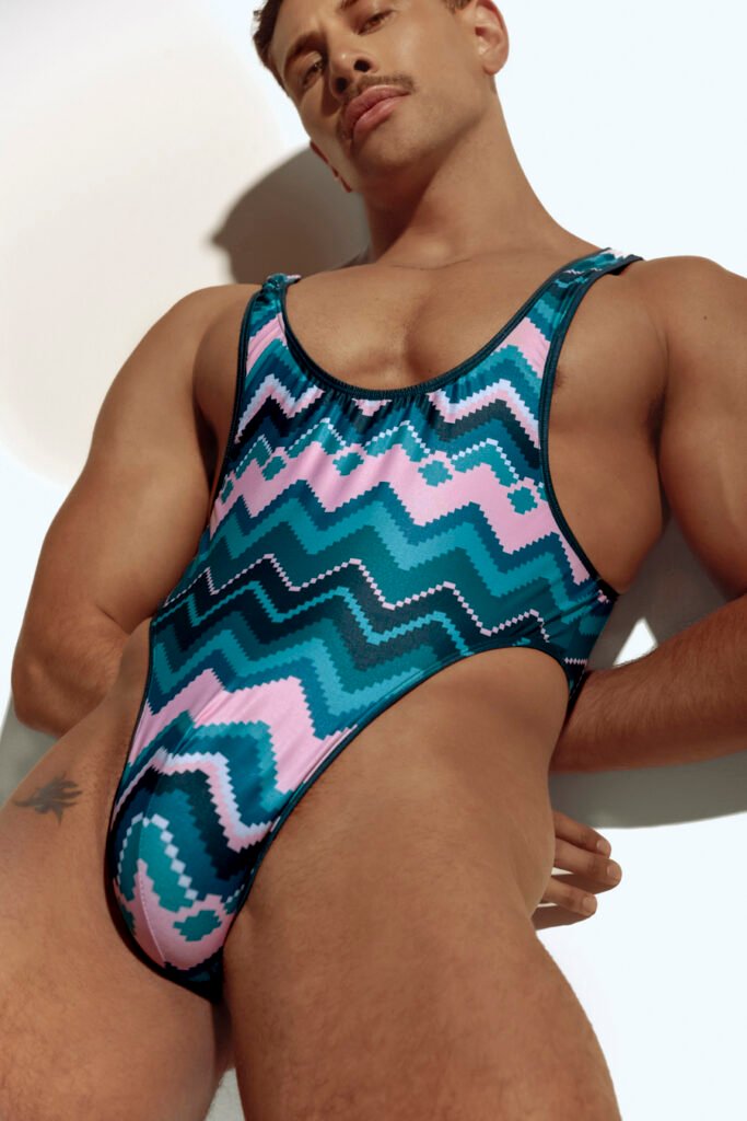 Men's high-cut swim bodysuit with bold chevron pattern in teal and pink, designed for gay men who love stylish and unique swimwear