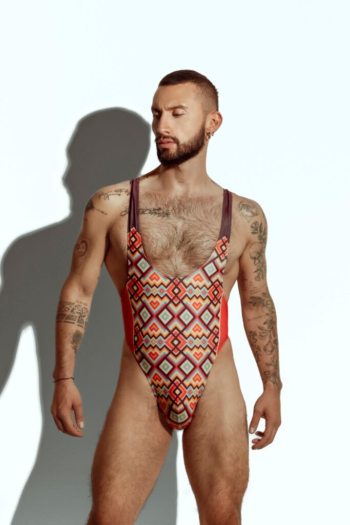 Men's high-cut swim bodysuit with orange and teal geometric pattern, designed for gay men seeking bold and fashionable swimwear