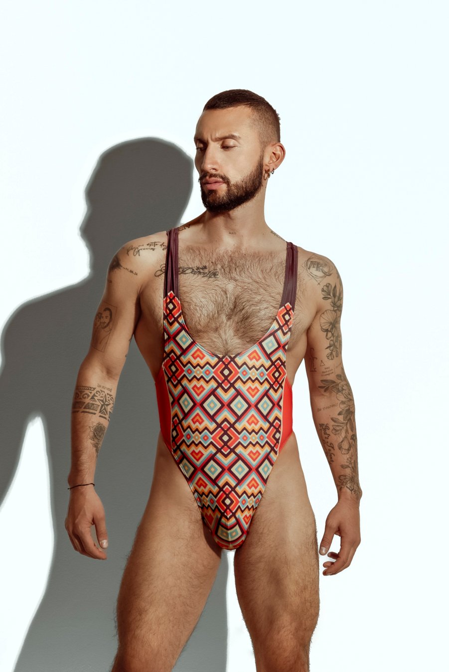 Men's high-cut swim bodysuit with orange and teal geometric pattern, designed for gay men seeking bold and fashionable swimwear