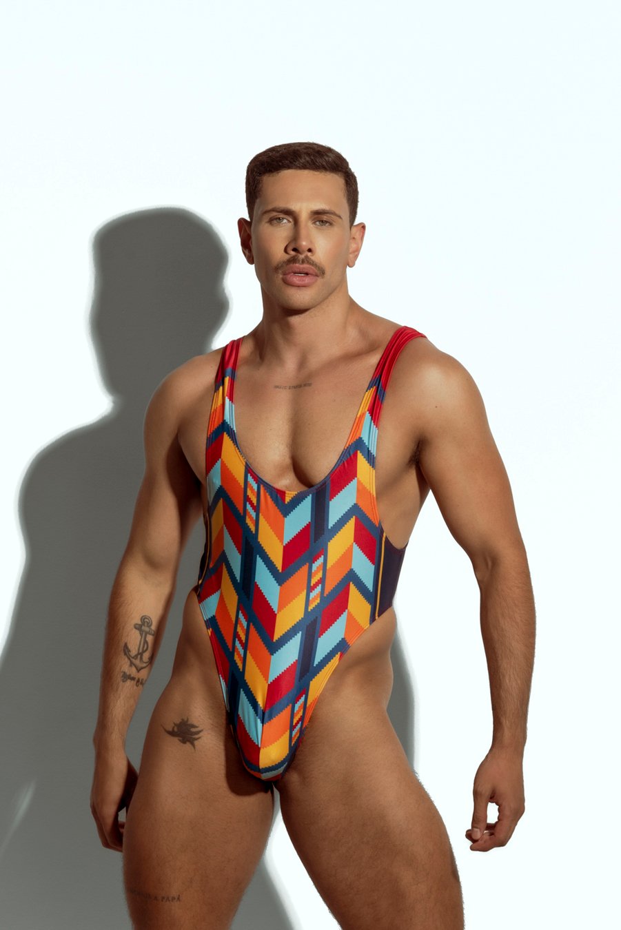 Men's high-cut swim bodysuit with orange and teal geometric pattern, designed for gay men seeking bold and fashionable swimwear