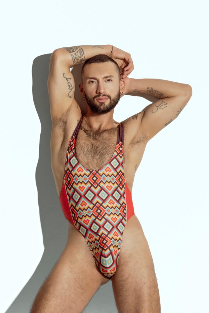 Men's high-cut swim bodysuit with orange and teal geometric pattern, designed for gay men seeking bold and fashionable swimwear