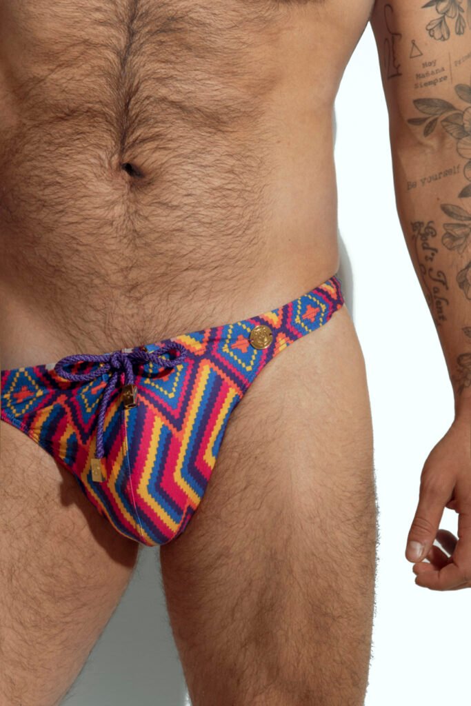 Men's swim thong with vibrant rainbow stripe pattern, designed for gay men looking for bold and colorful beachwear