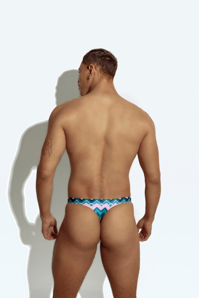 Men's thong swimwear with vibrant chevron pattern in pink, blue, and teal, designed for the gay community