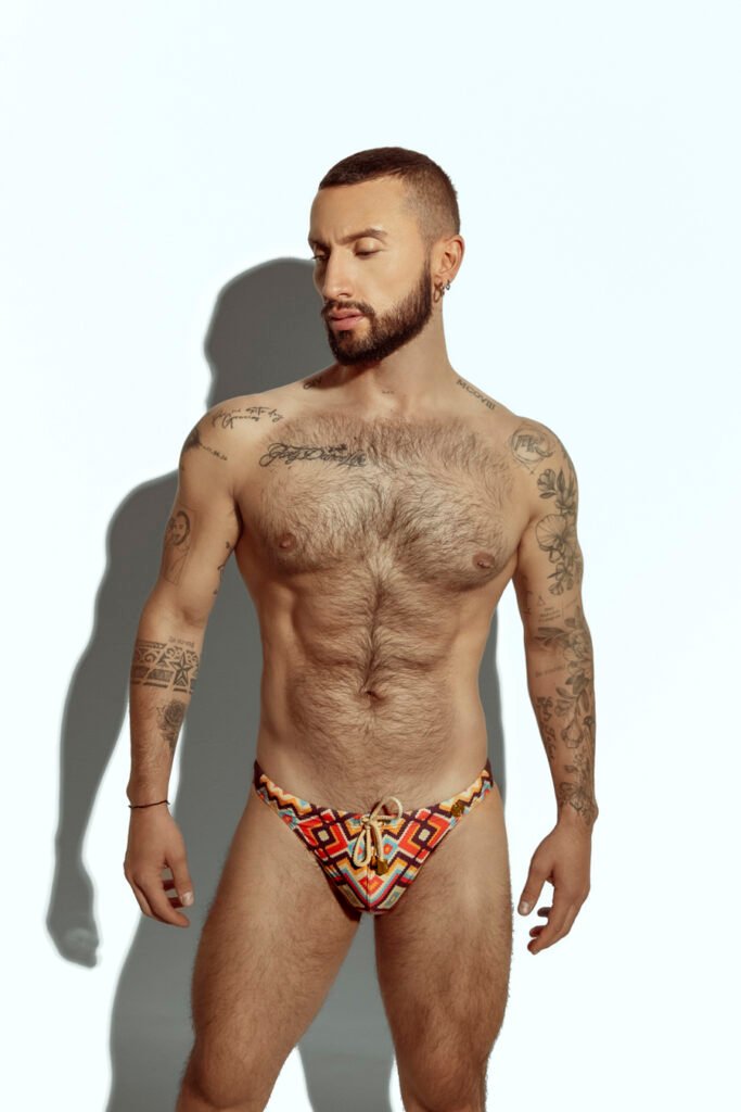 Men's swim thong featuring a bold zigzag pattern in red, orange, and yellow, ideal for gay men seeking stylish and eye-catching swimwear