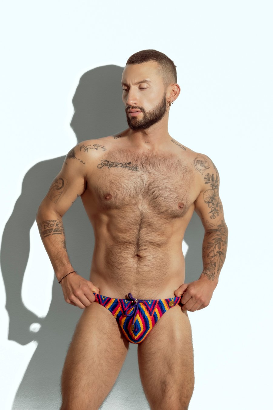 Men's swim brief with vibrant rainbow stripe pattern, designed for gay men looking for bold and colorful beachwear