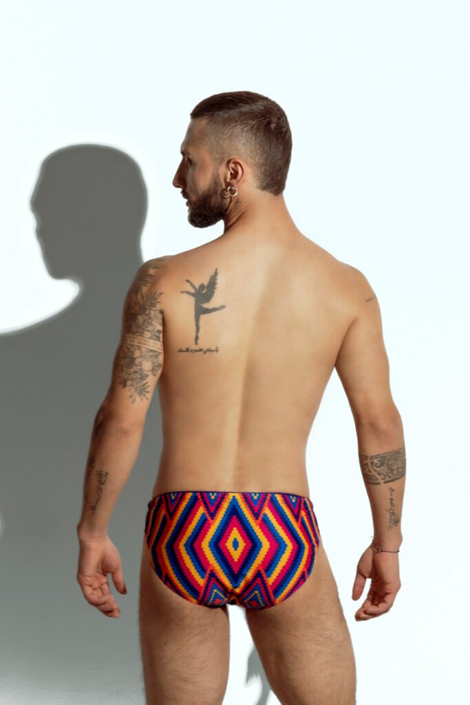 Men's swim brief with vibrant rainbow stripe pattern, designed for gay men looking for bold and colorful beachwear