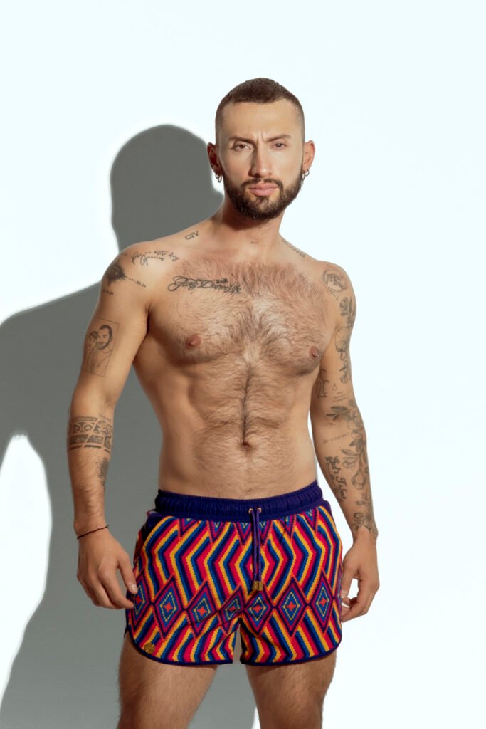 Men's swim short with vibrant rainbow stripe pattern, designed for gay men looking for bold and colorful beachwear