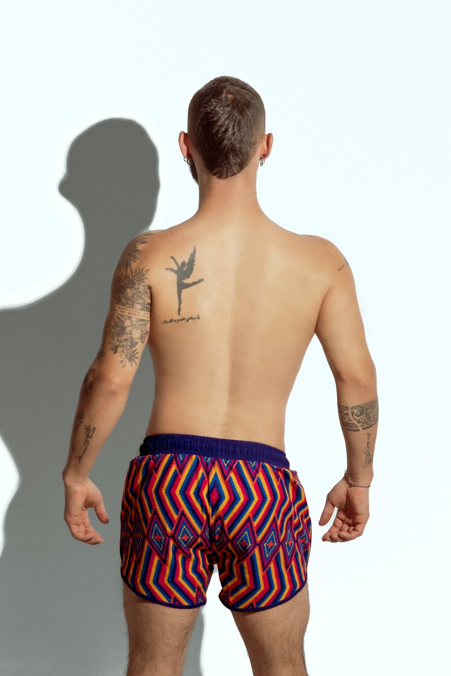 Men's swim short with vibrant rainbow stripe pattern, designed for gay men looking for bold and colorful beachwear