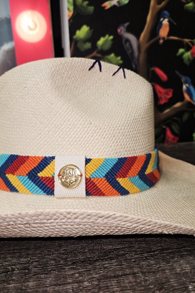 Handmade straw hat with vibrant Wayuu band by Colombian artisans. Perfect for beach, poolside relaxation, or summer cocktails. Stylish and unique